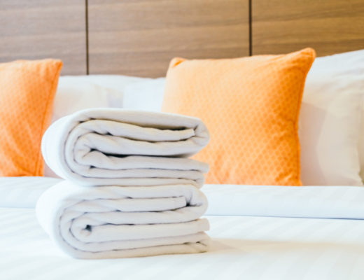white bath towel on bed, orange pillow