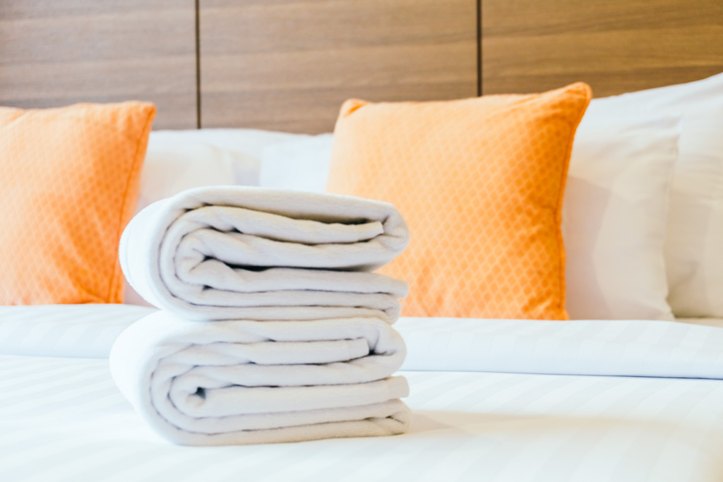 white bath towel on bed, orange pillow