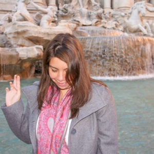 Woman throwing coin at Fontana di Trevi, Italy