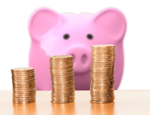 TravelAfter5_Dumb Travel Money Saving_Pink Piggy Bank looking at stacks of coins
