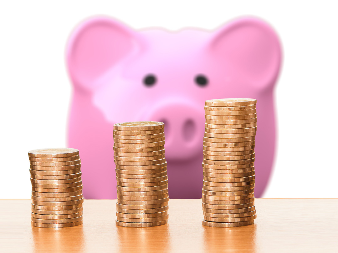 TravelAfter5_Dumb Travel Money Saving_Pink Piggy Bank looking at stacks of coins